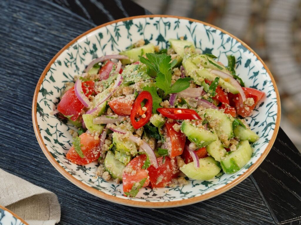 A colorful and fresh vegetable salad featuring cucumbers, tomatoes, and herbs, perfect for a summer meal.