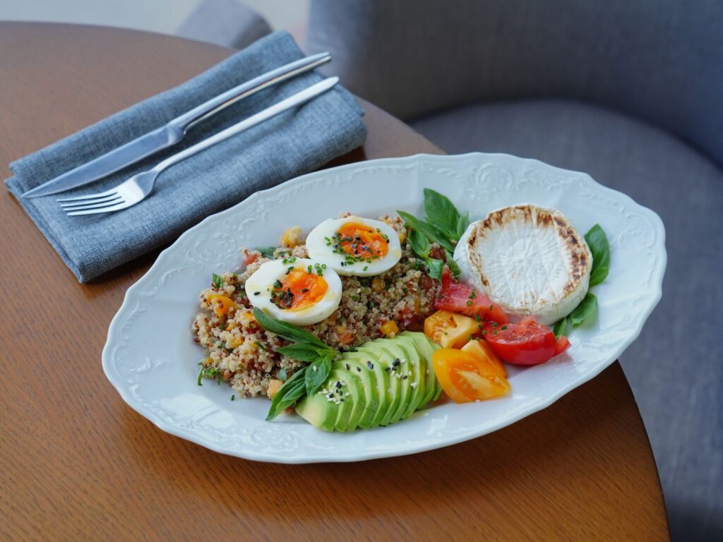 Delicious quinoa salad with sliced avocado, soft-boiled eggs, and fresh herbs.