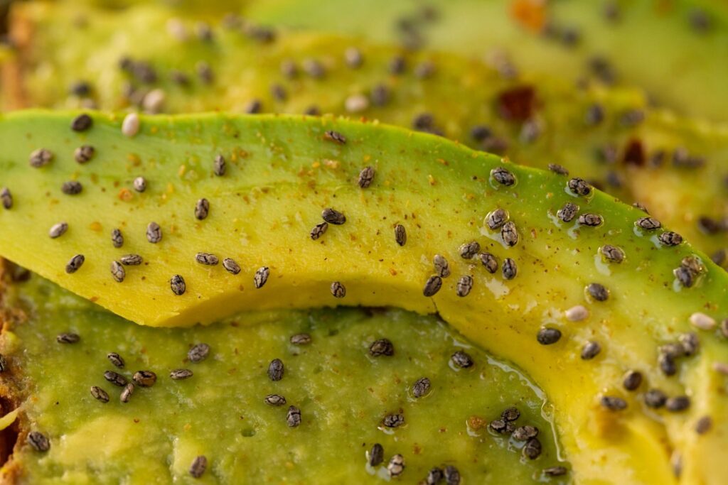 Detailed macro shot of fresh avocado slices topped with chia seeds.