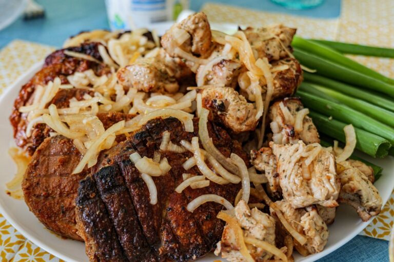 Delicious grilled meat with onions and fresh vegetables, perfect for a hearty meal.