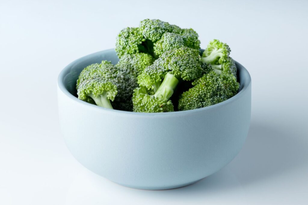 Close-up of fresh broccoli florets in a minimal light blue bowl, showcasing healthy eating.