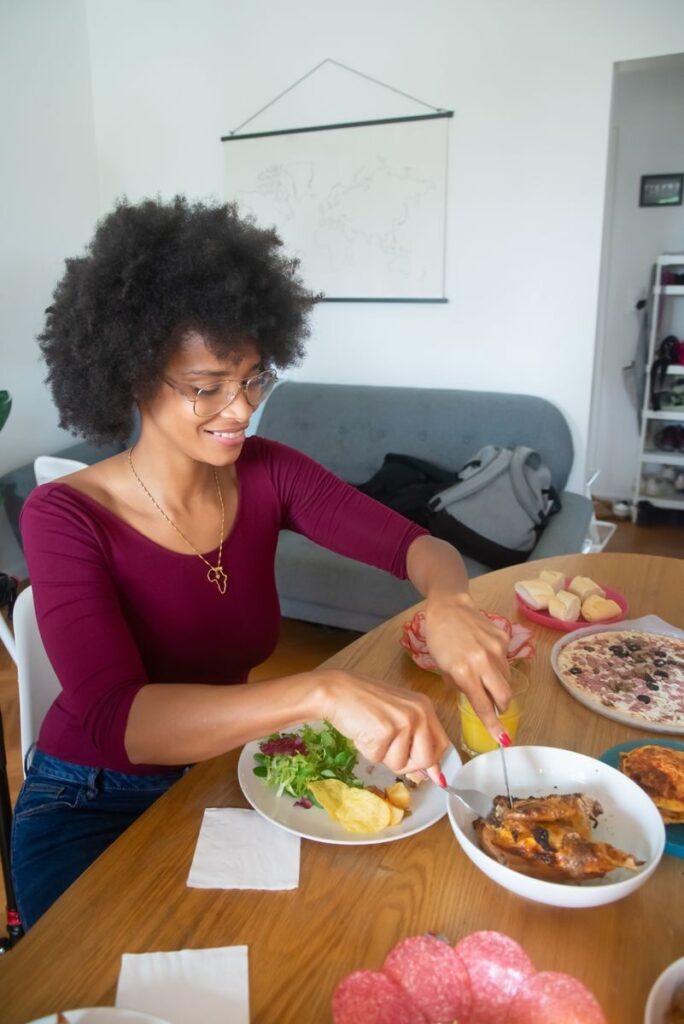 African American woman with afro hair dining at home, enjoying a delicious meal.