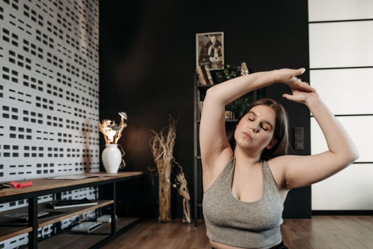 Adult woman doing yoga exercises in a modern home setting with eyes closed.