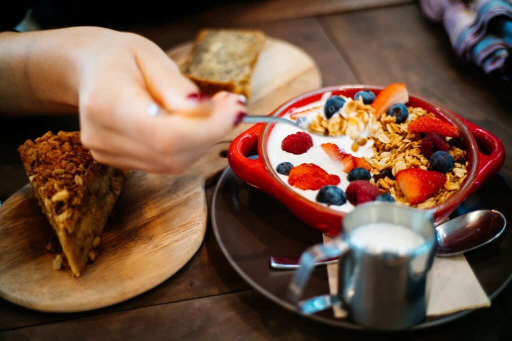 15 Aliments Riches en Protéines Pour les Sportifs d’Endurance | Santé et bien-être Close-up of a breakfast setting with granola, fresh berries, and a slice of cake.
