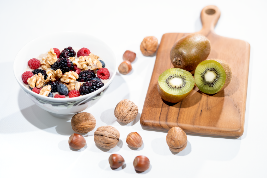 Les 10 meilleurs aliments anti-cholestérol à intégrer dans votre quotidien | Santé et bien-être A vibrant bowl of mixed berries, walnuts, and kiwi on a cutting board. Perfect for a healthy breakfast.