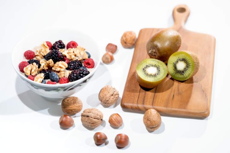 Les 10 meilleurs aliments anti-cholestérol à intégrer dans votre quotidien | Santé et bien-être A vibrant bowl of mixed berries, walnuts, and kiwi on a cutting board. Perfect for a healthy breakfast.