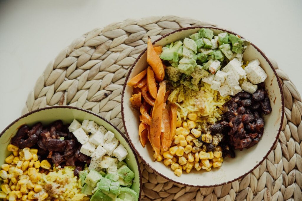 15 Aliments Riches en Protéines Pour les Sportifs d’Endurance | Santé et bien-être Top view of vegetarian bowls with avocado, corn, beans, and cheese for a delicious meal.
