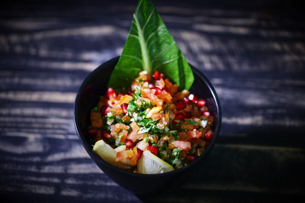 Les 10 meilleurs aliments anti-cholestérol à intégrer dans votre quotidien | Santé et bien-être Bright and colorful fresh salsa in a black bowl with a rustic background, featuring pomegranate, tomato, and herbs.